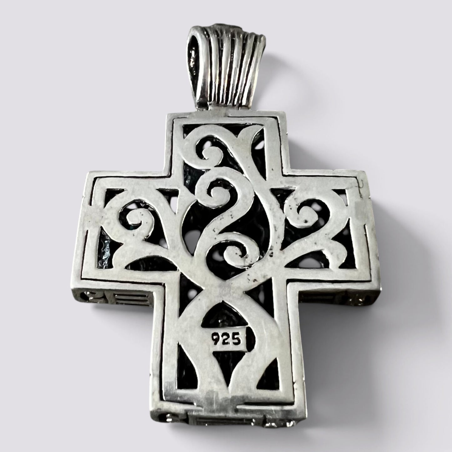 A sterling silver Orthodox cross pendant with intricate filigree cutouts and a bail, featuring a '925' silver purity stamp on the lower crossbar, set against a plain light gray background.