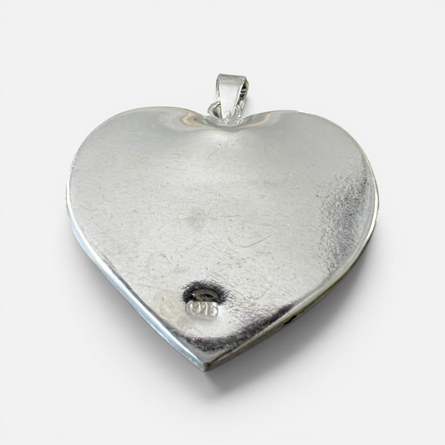 A polished silver heart-shaped pendant with a textured finish and a small bail at the top, shown on a clean white background and the 925 stamp.