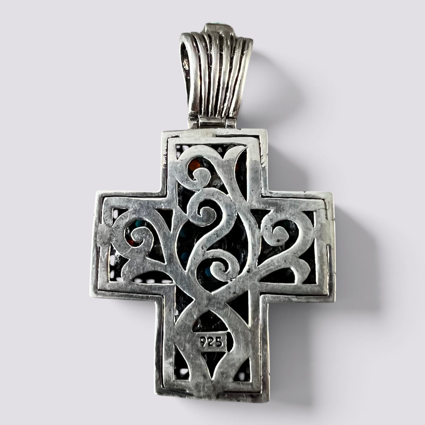 A sterling silver cross pendant with intricate filigree cutouts and a textured bail, shown on a light gray background.