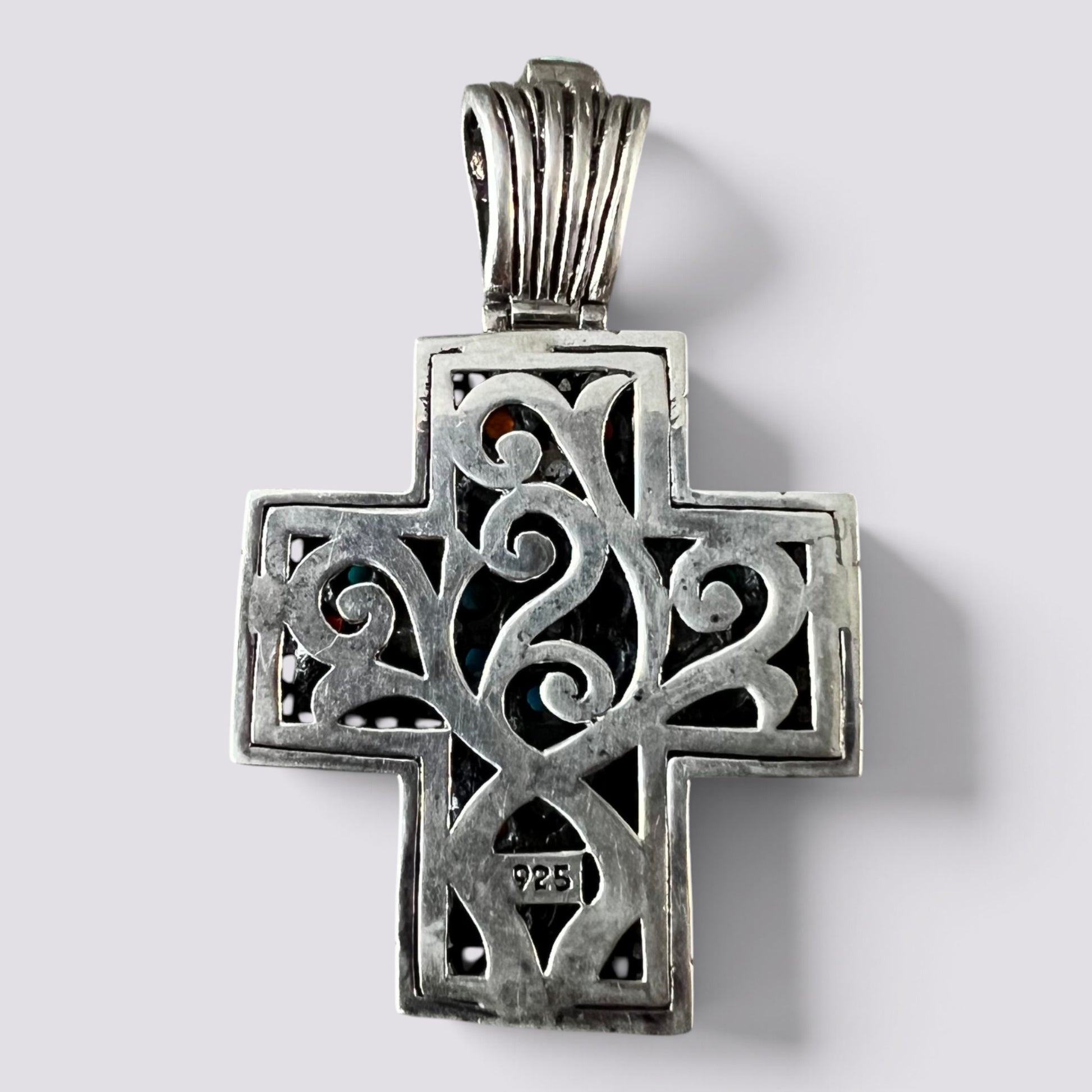 A sterling silver cross pendant with intricate filigree cutouts and a textured bail, shown on a light gray background.