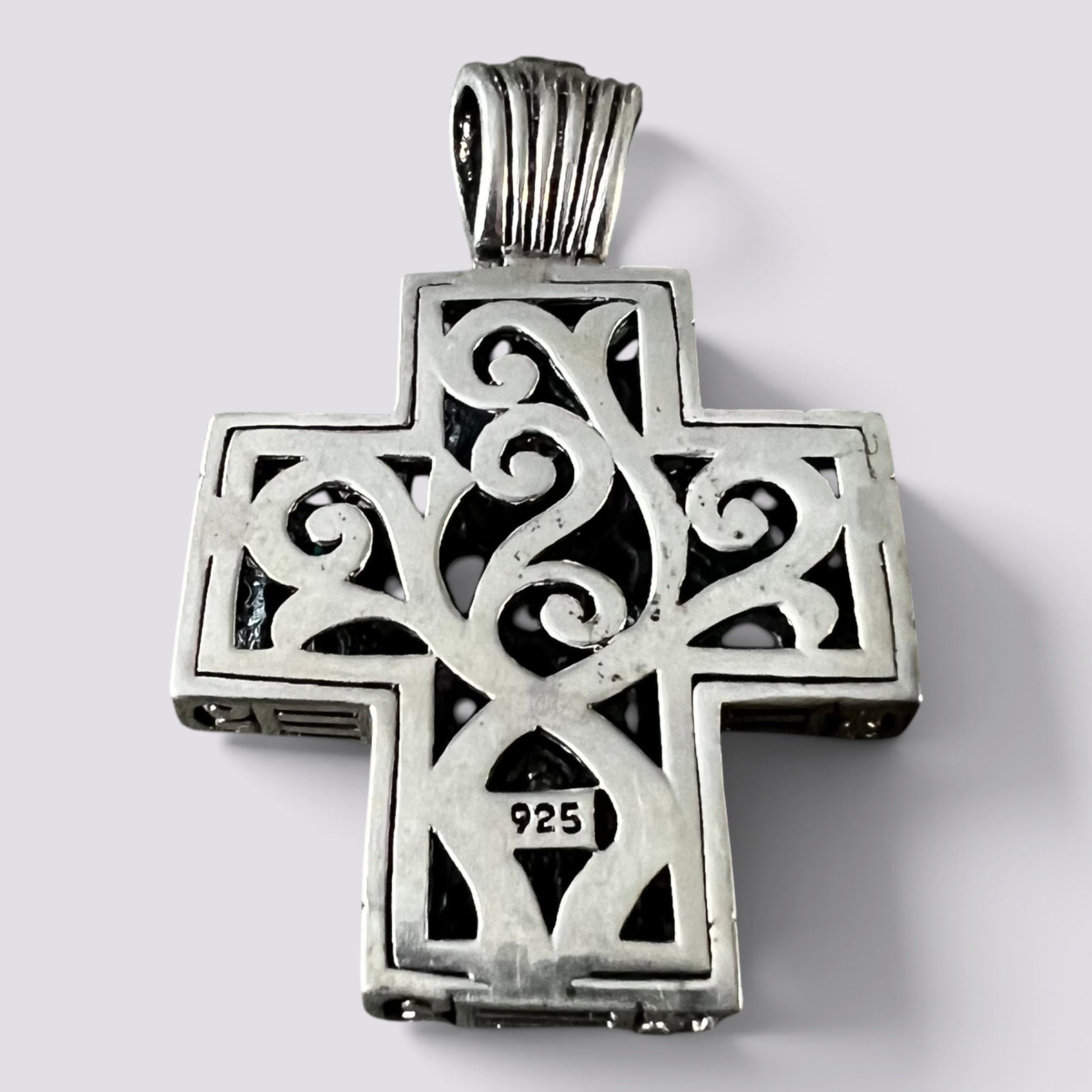 A sterling silver Orthodox cross pendant with intricate filigree cutouts and a bail, featuring a '925' silver purity stamp on the lower crossbar, set against a plain light gray background.