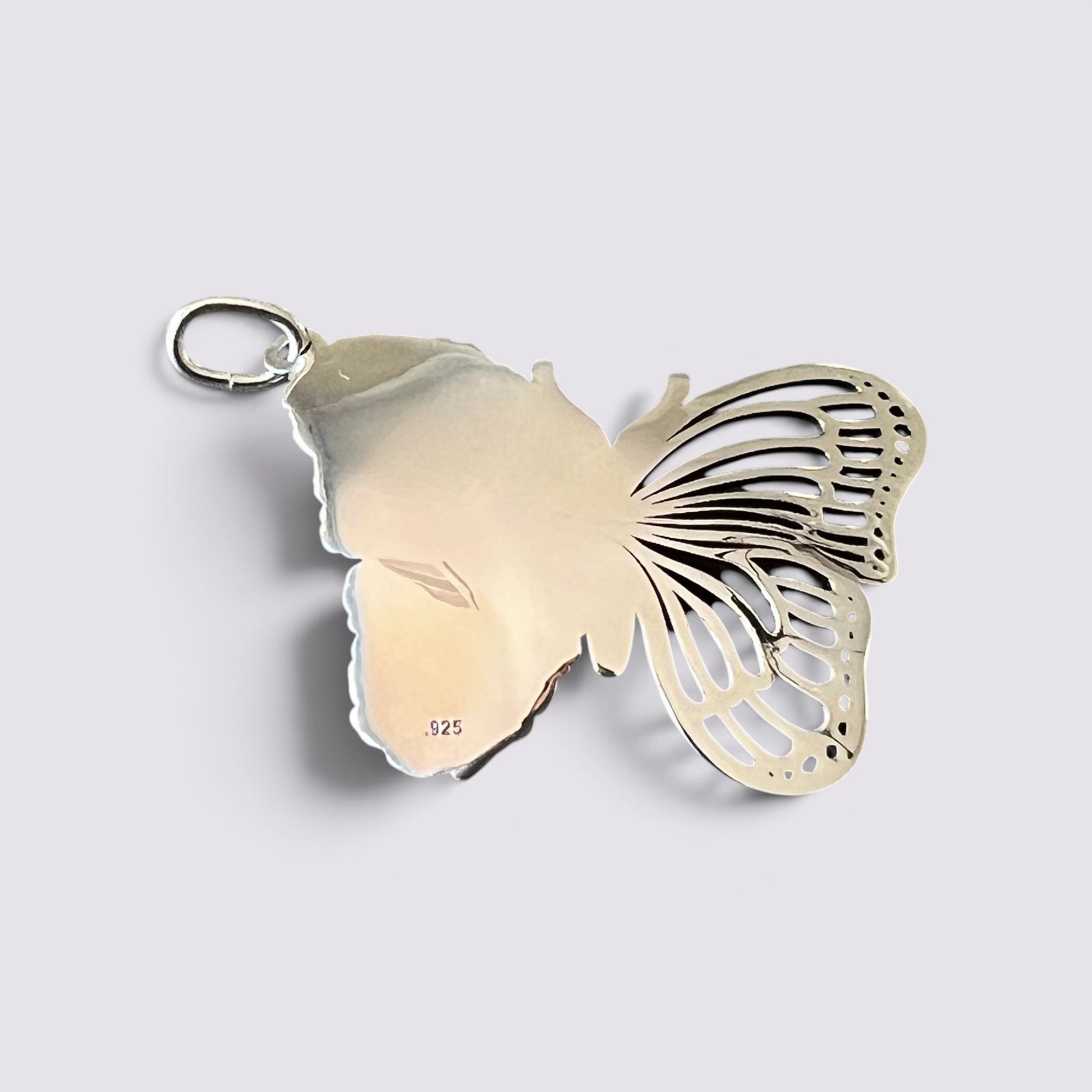 A butterfly-shaped pendant charm made of sterling silver, featuring a polished left wing and an openwork, filigree-style right wing with a small hanging loop at the top, shown on a light gray background.
