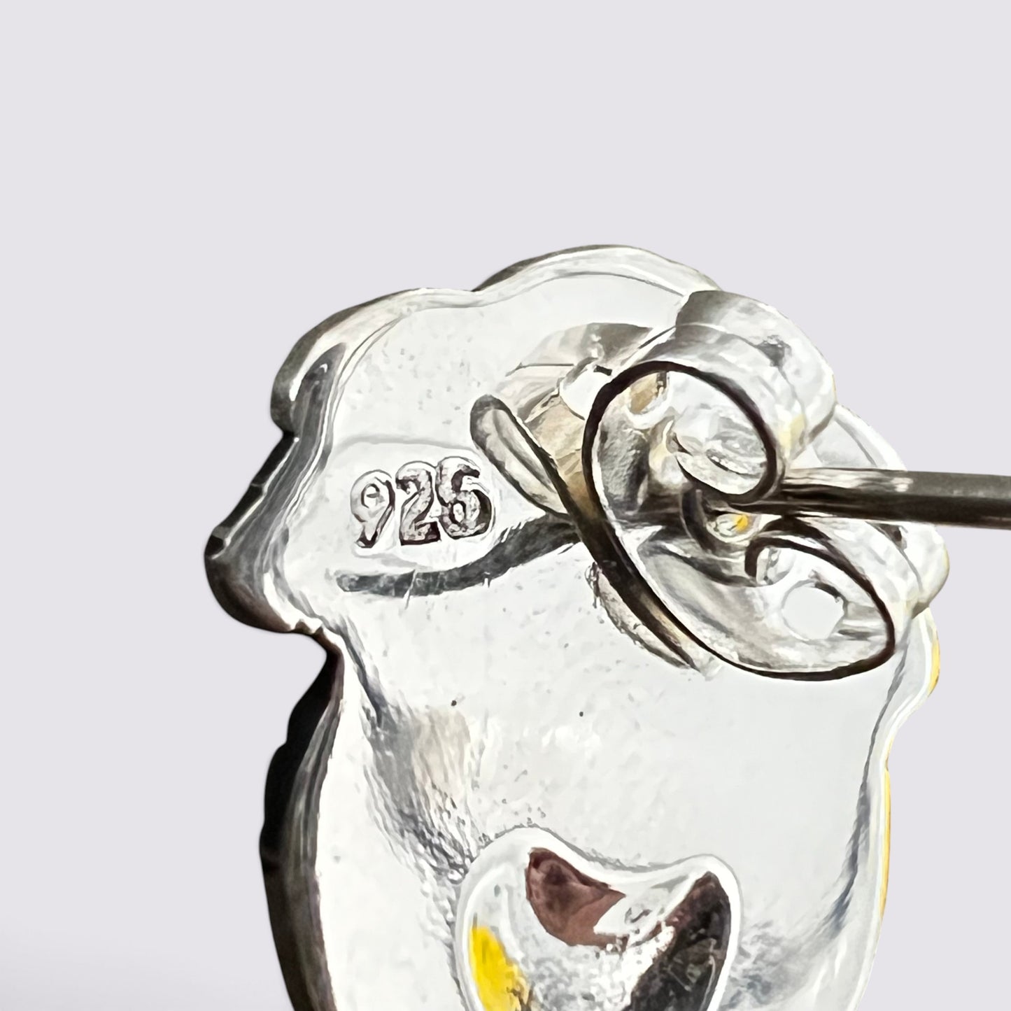 Close-up of a silver-toned jewelry piece with a hammered finish and a small engraved '925' mark, shown against a light gray background.