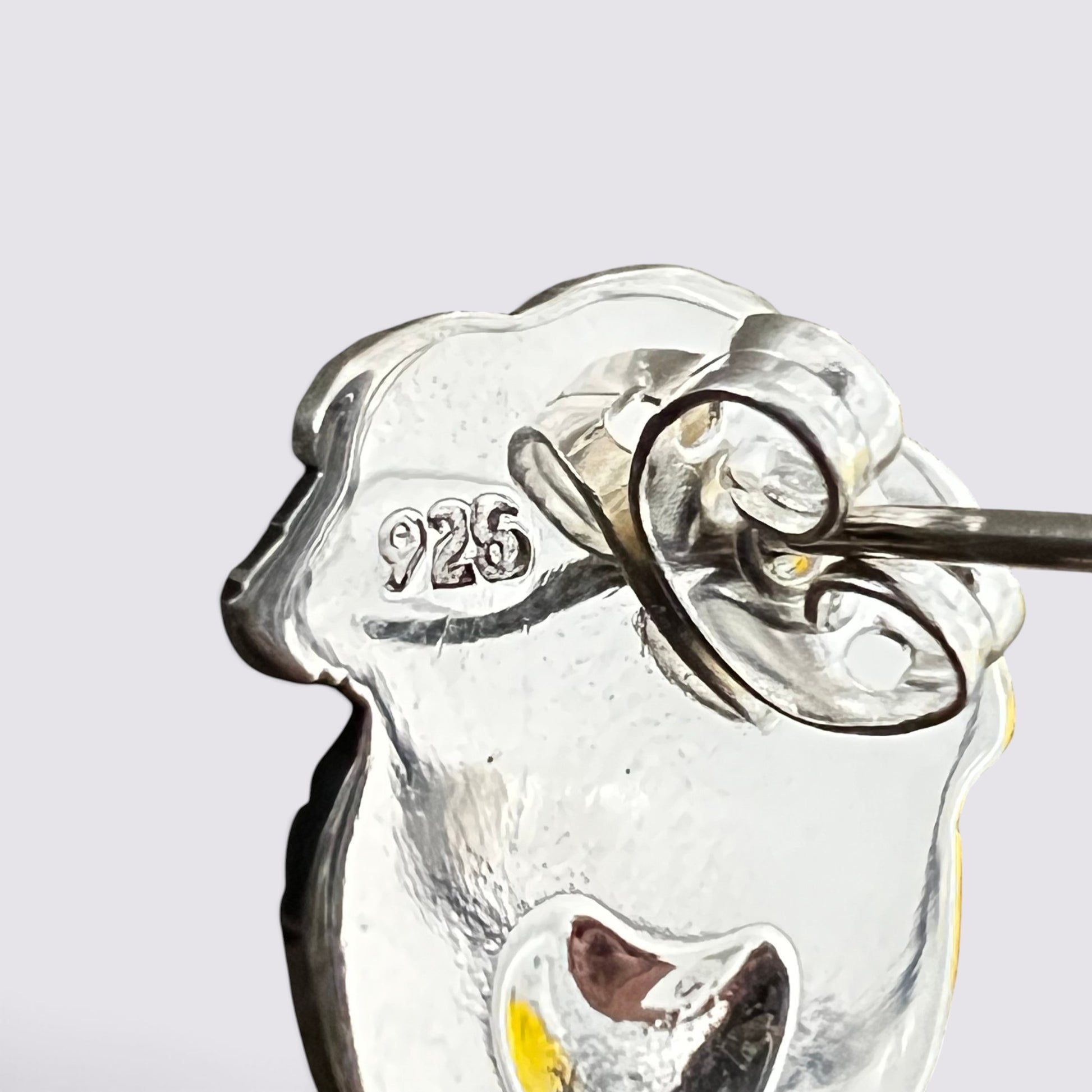 Close-up of a silver-toned jewelry piece with a hammered finish and a small engraved '925' mark, shown against a light gray background.