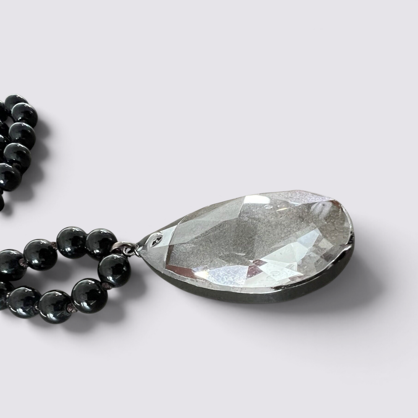 The Fashion Jewels black beaded necklace featuring a large clear faceted glass teardrop pendant on a white background