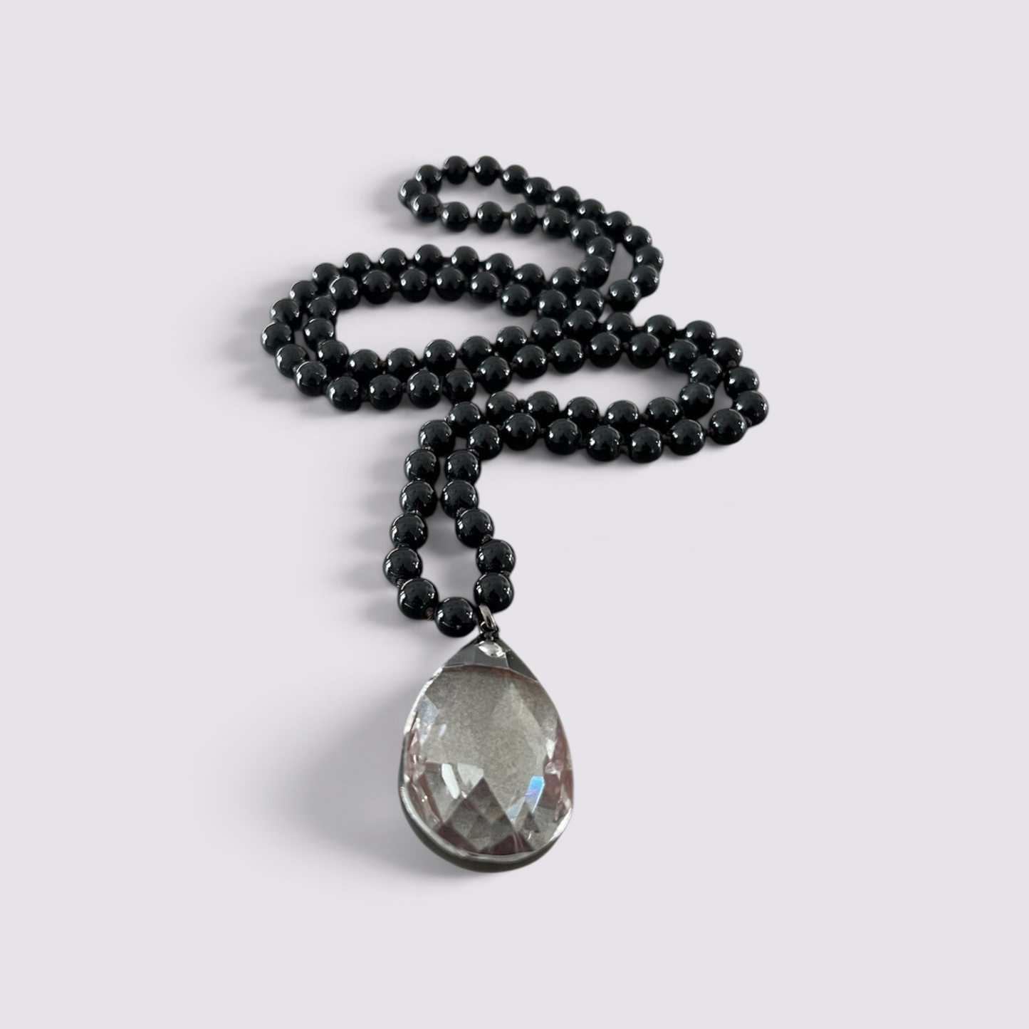 The Fashion Jewels layered necklace featuring a long strand of smooth black beads and a large clear glass teardrop pendant