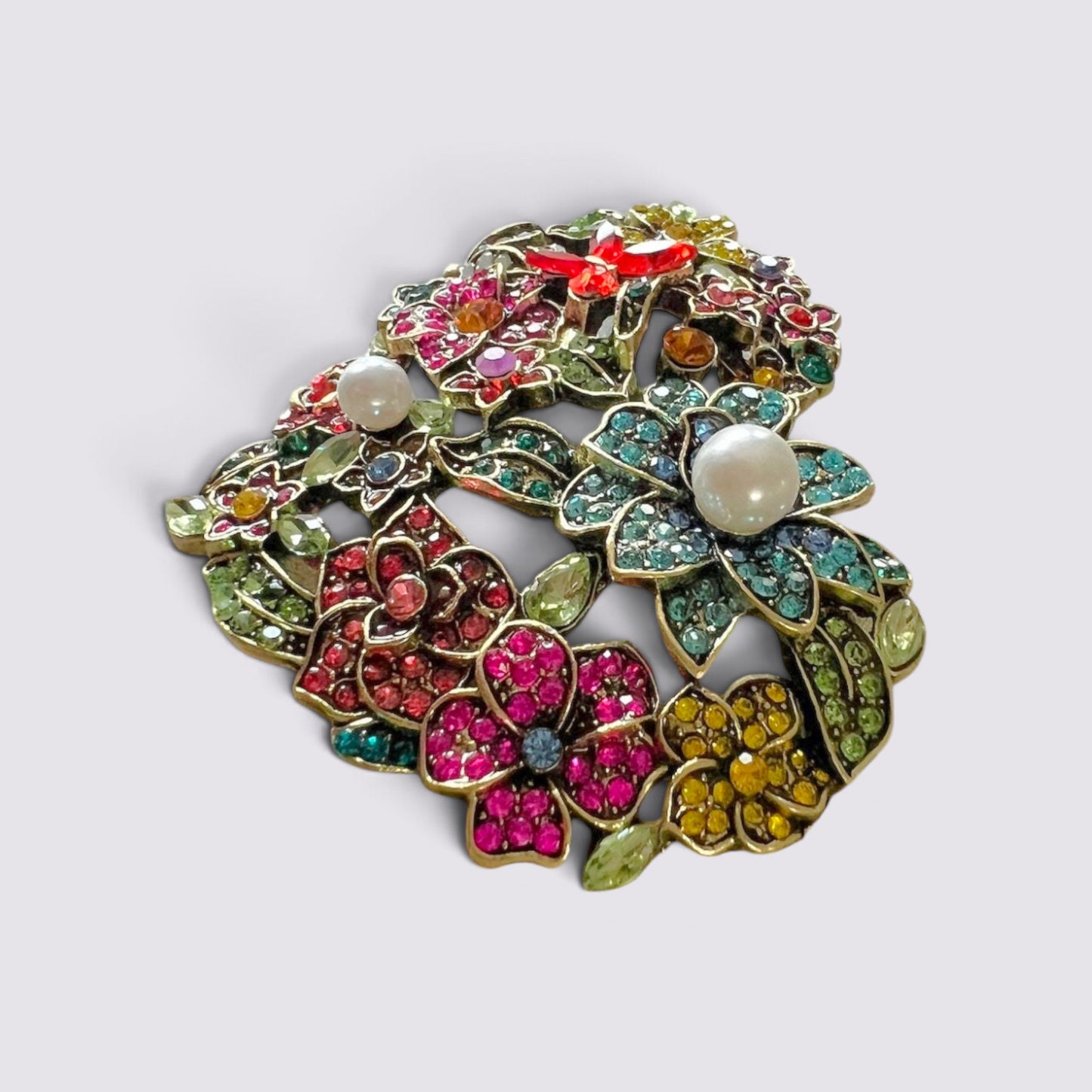 The Fashion Jewels heart-shaped brooch featuring multi-colored crystals, floral motifs, and faux pearl accents.