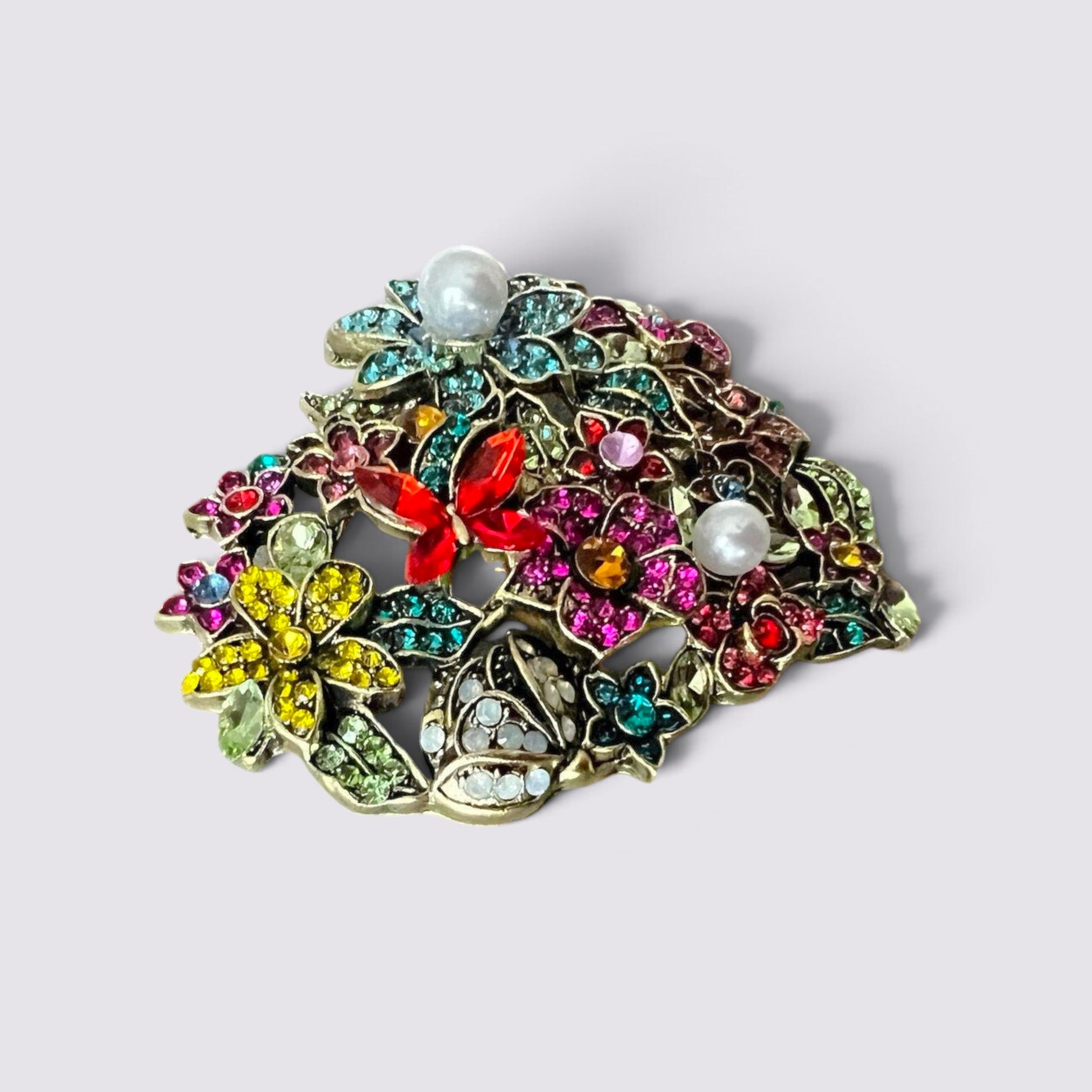 The Fashion Jewels heart-shaped brooch featuring multi-colored crystals, floral motifs, and faux pearl accents.