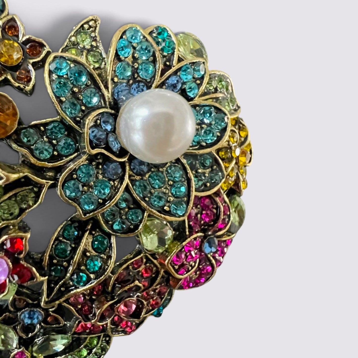 The Fashion Jewels heart-shaped brooch with multi-colored crystals, floral motifs, and a central faux pearl accent.