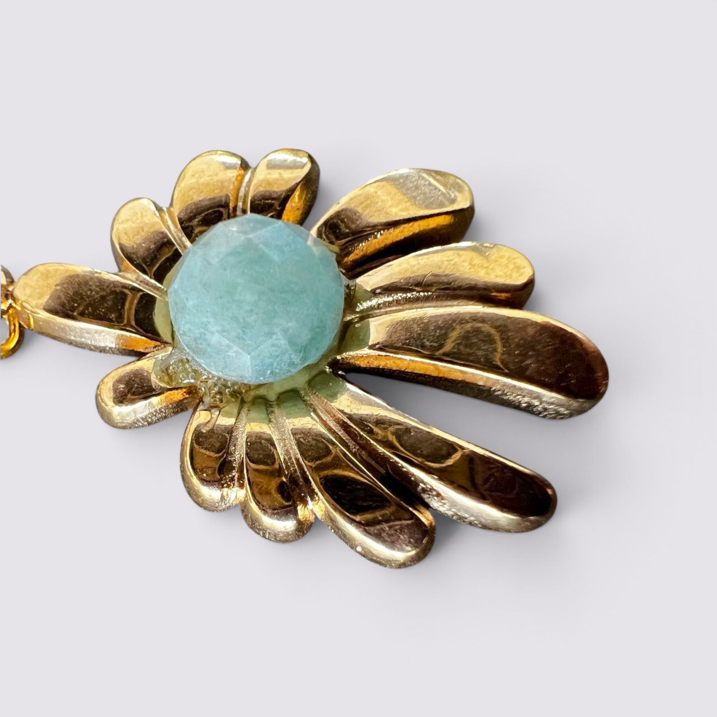 The Fashion Jewels floral drop earrings featuring a polished gold-tone metal petal motif and a faceted green stone.