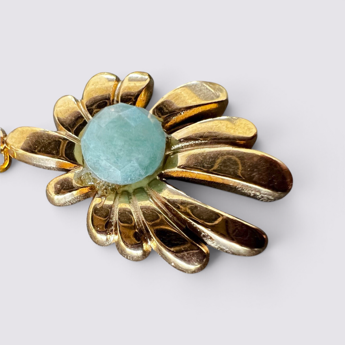 The Fashion Jewels floral drop earrings featuring a polished gold-tone metal petal motif and a faceted green stone.