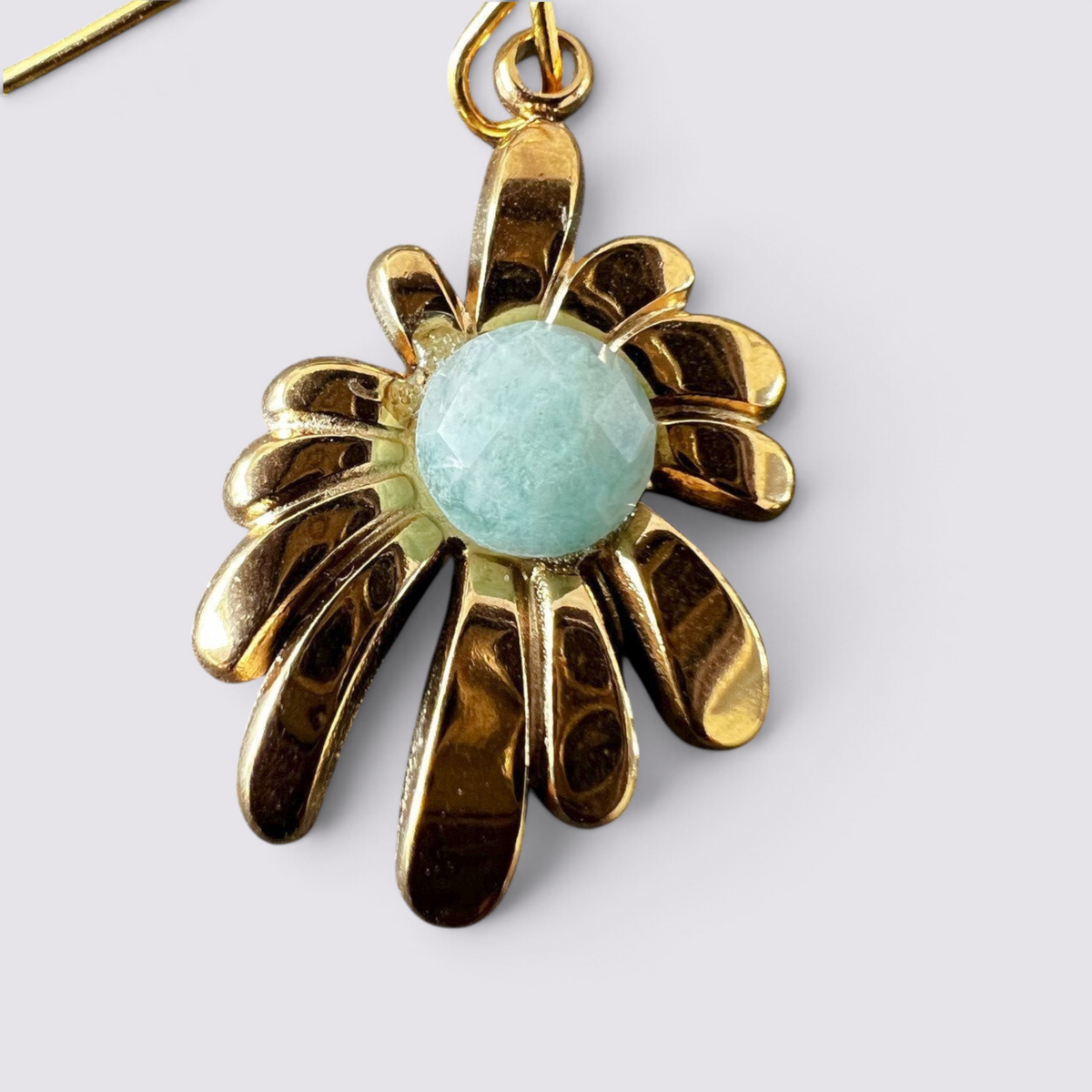 The Fashion Jewels floral drop earrings featuring a polished gold-tone sunburst petal design and a faceted green stone.