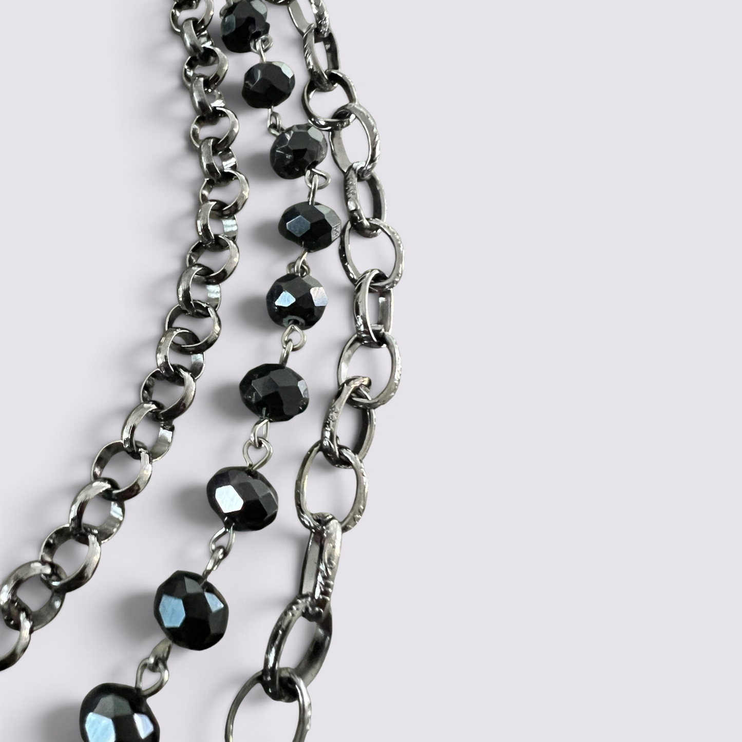 The Fashion Jewels layered necklace set featuring faceted black beads and dark metal chain links on a white background