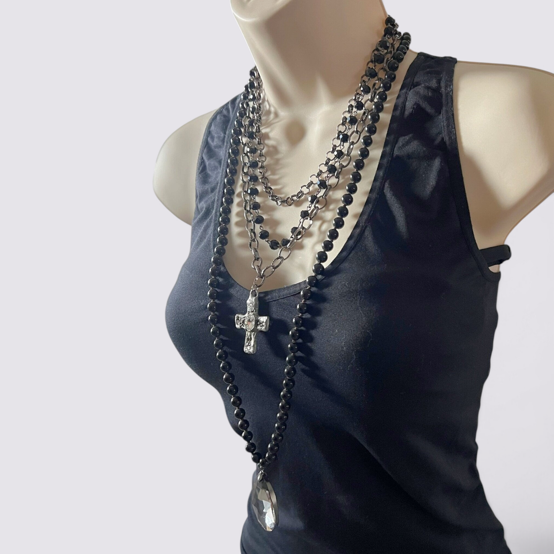 The Fashion Jewels layered necklace set featuring black beads, silver chains, a crystal cross, and a teardrop pendant.