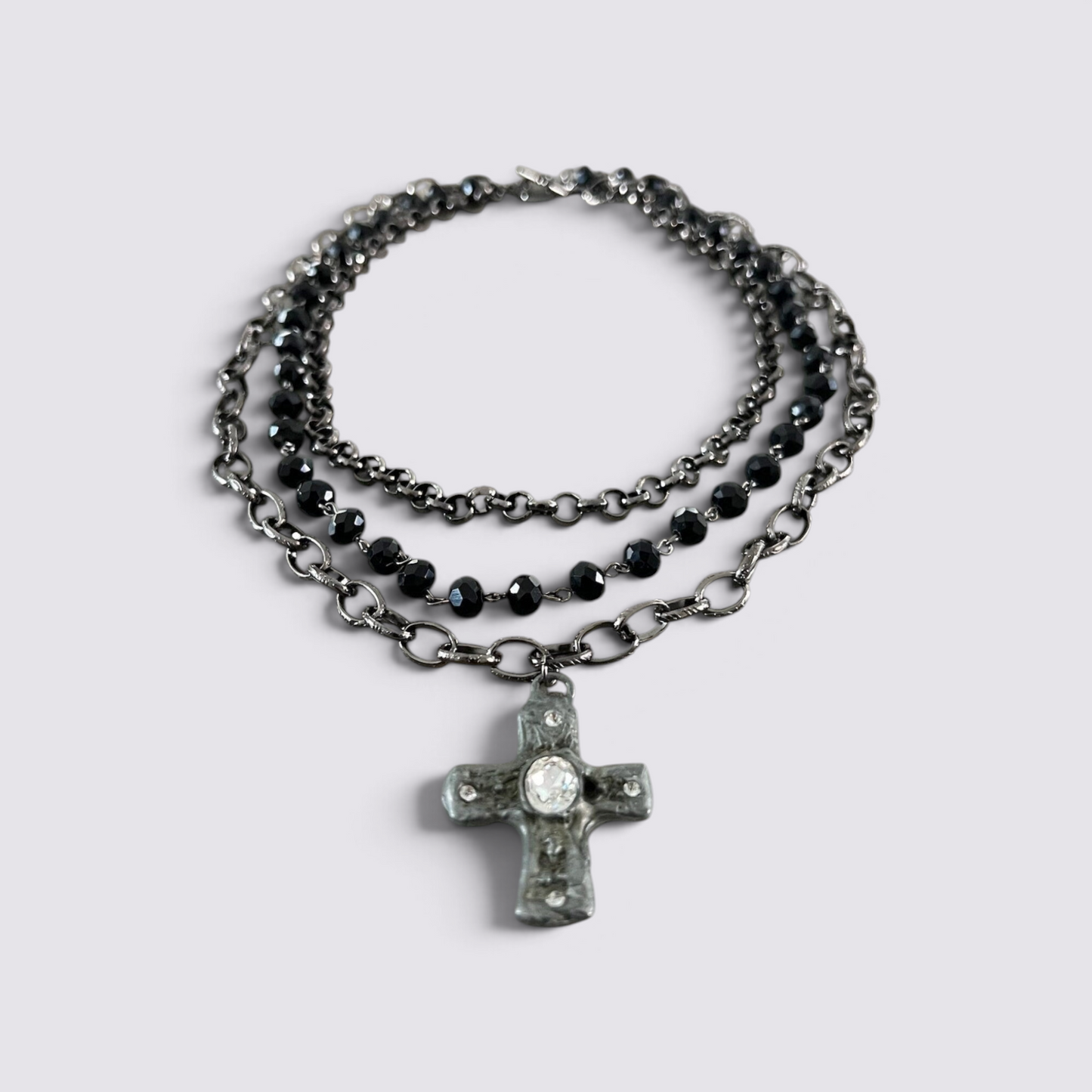 The Fashion Jewels layered necklace set featuring black faceted beads, dark metal chains, and a crystal cross pendant.