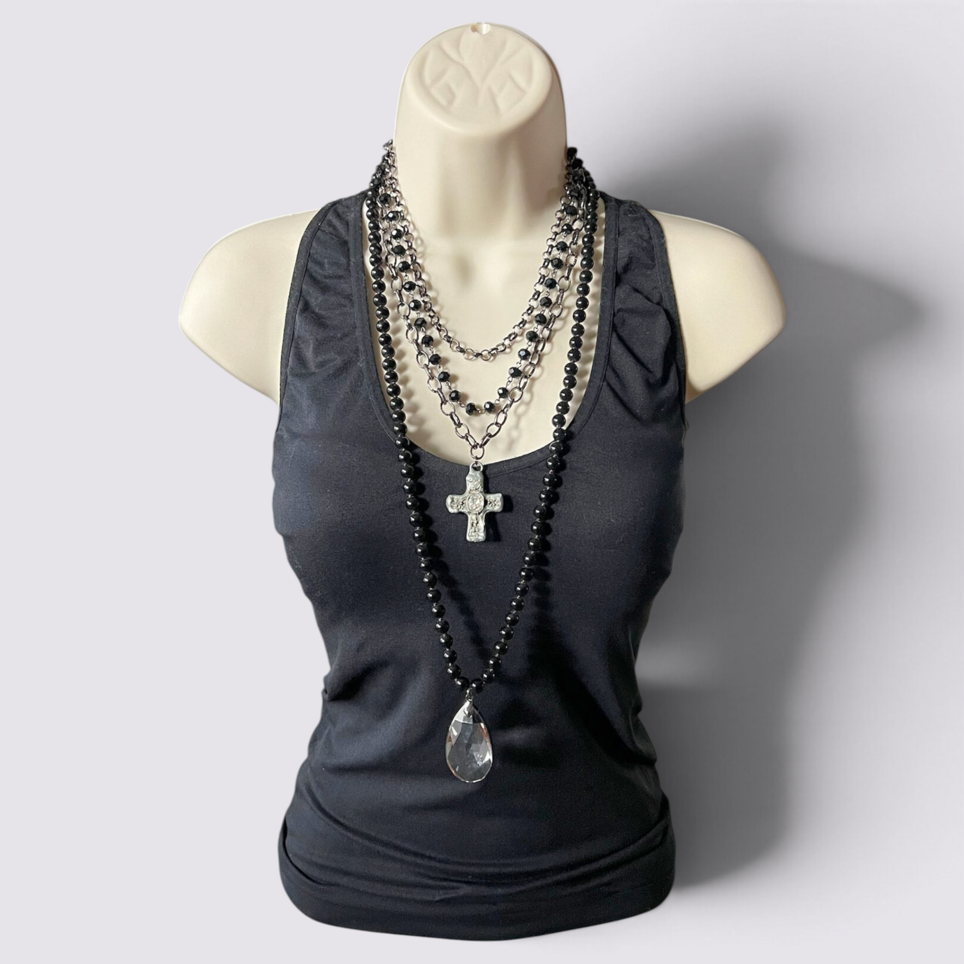 The Fashion Jewels layered necklace set featuring black beads, a crystal teardrop pendant, and a crystal cross charm.