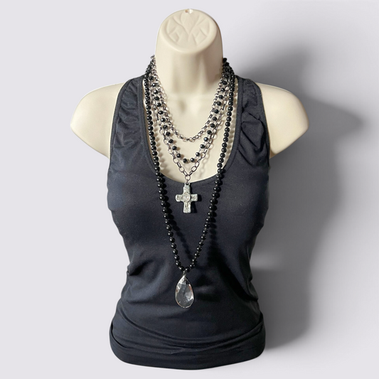 The Fashion Jewels layered necklace set featuring black beads, a crystal teardrop pendant, and a crystal cross charm.