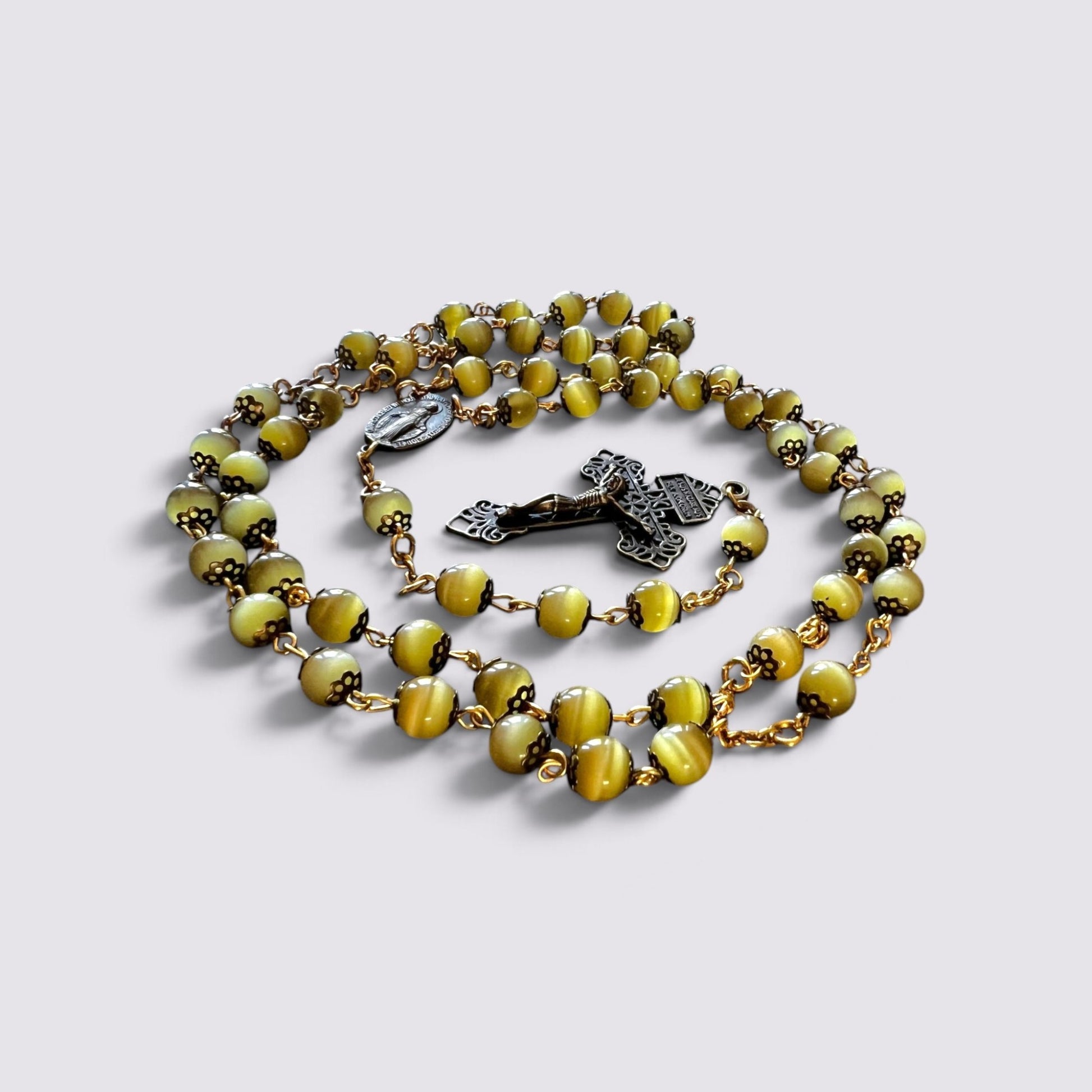 The Fashion Jewels olive cat's eye bead rosary with antique metal caps, gold-toned chain, and ornate crucifix.