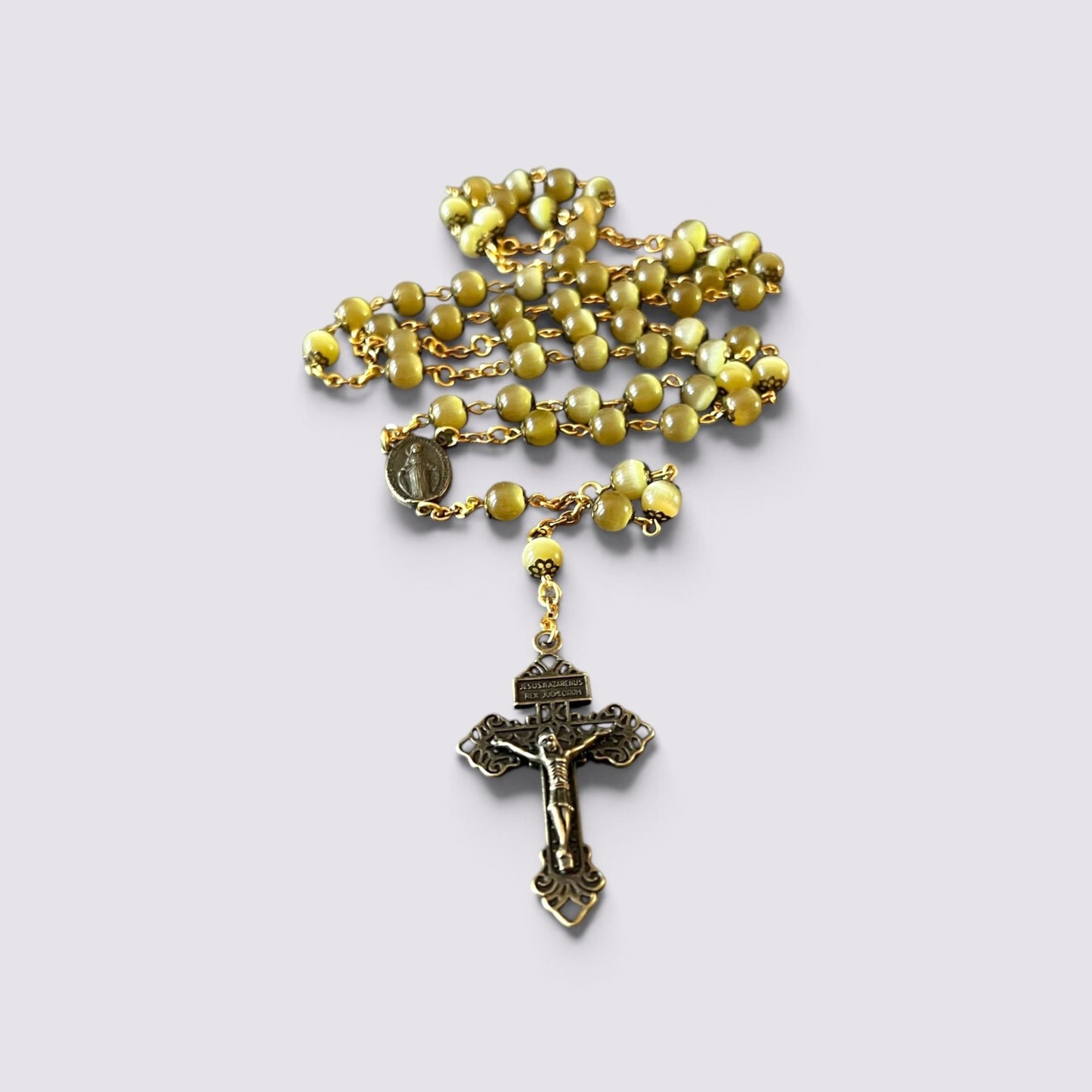 The Fashion Jewels rosary with olive cat's eye beads, antique metal caps, gold chain, and ornate crucifix centerpiece.