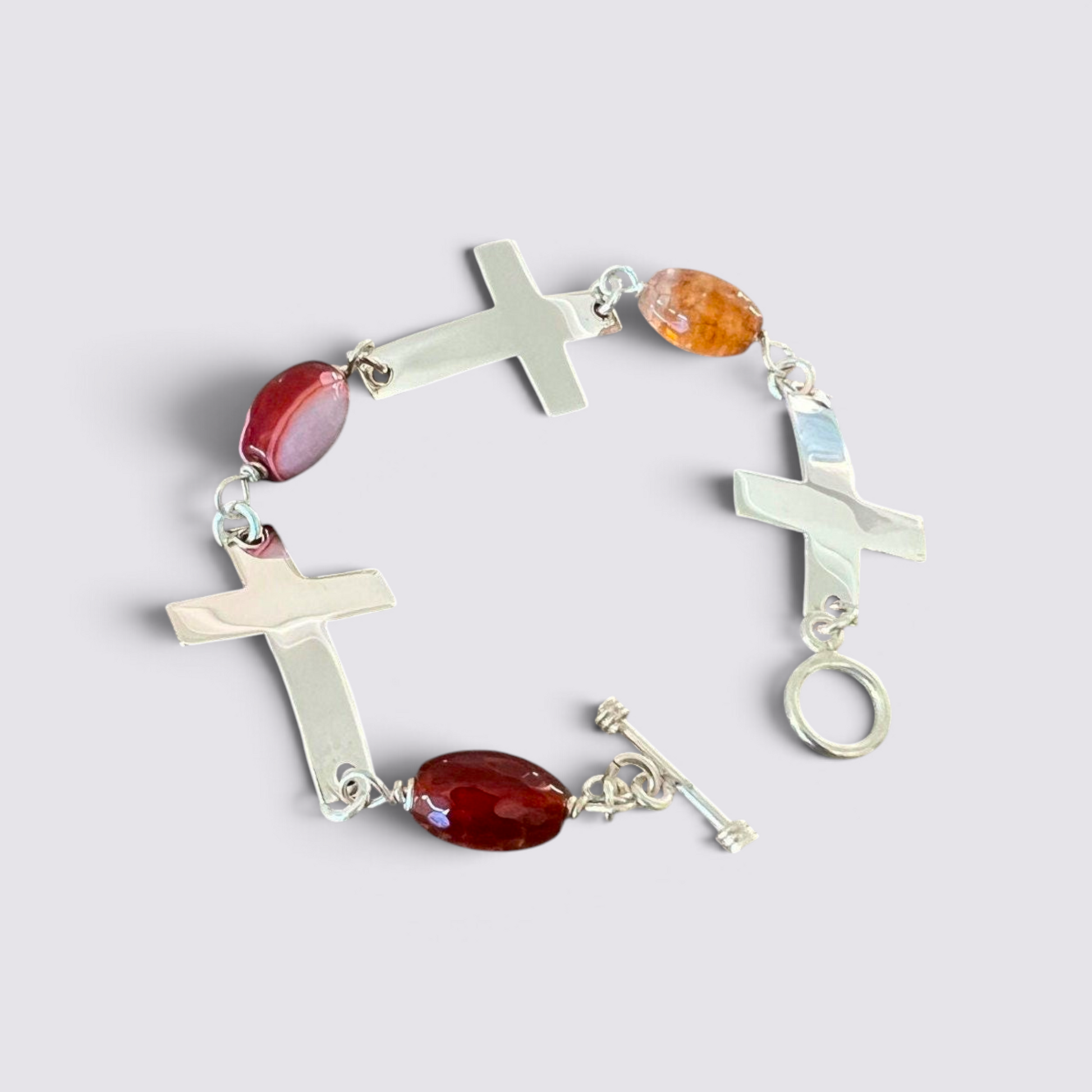 The Fashion Jewels sterling silver cross bracelet with faceted red and orange carnelian beads and a toggle clasp.