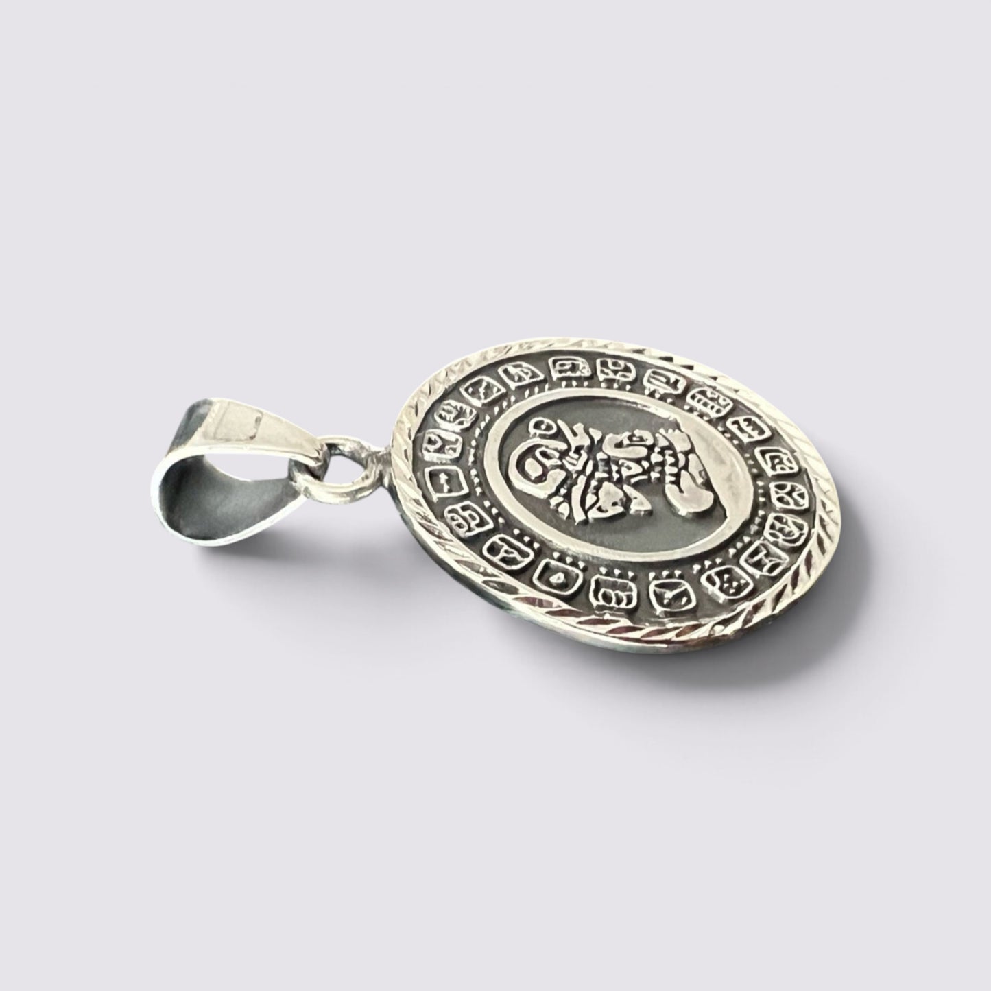 The Fashion Jewels handmade silver Mayan calendar pendant featuring intricate engraved details on a circular charm.