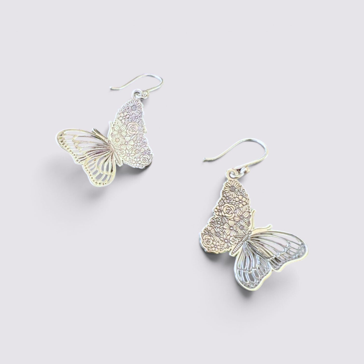 The Fashion Jewels sterling silver butterfly drop earrings with intricate floral etched wing detailing on a light background