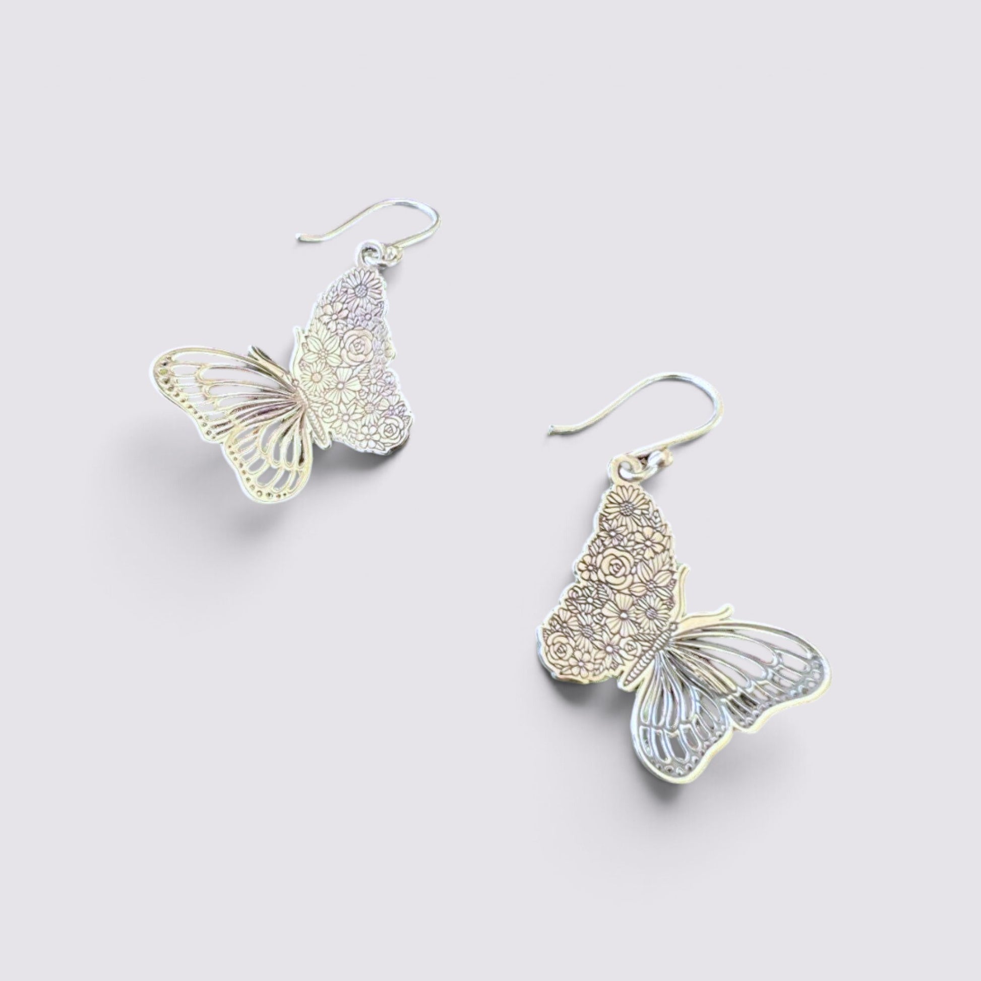 The Fashion Jewels sterling silver butterfly drop earrings with intricate floral etched wing detailing on a light background