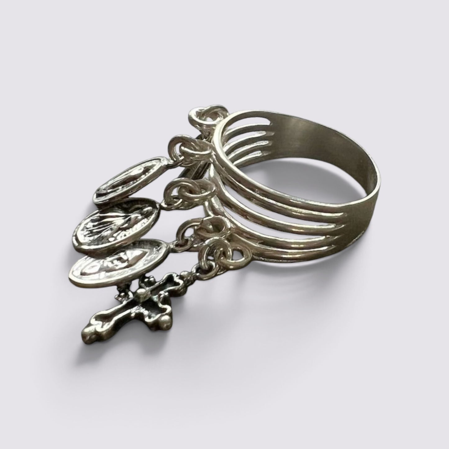 The Fashion Jewels sterling silver ring featuring five hanging religious charms and a cross on a dark grey surface.