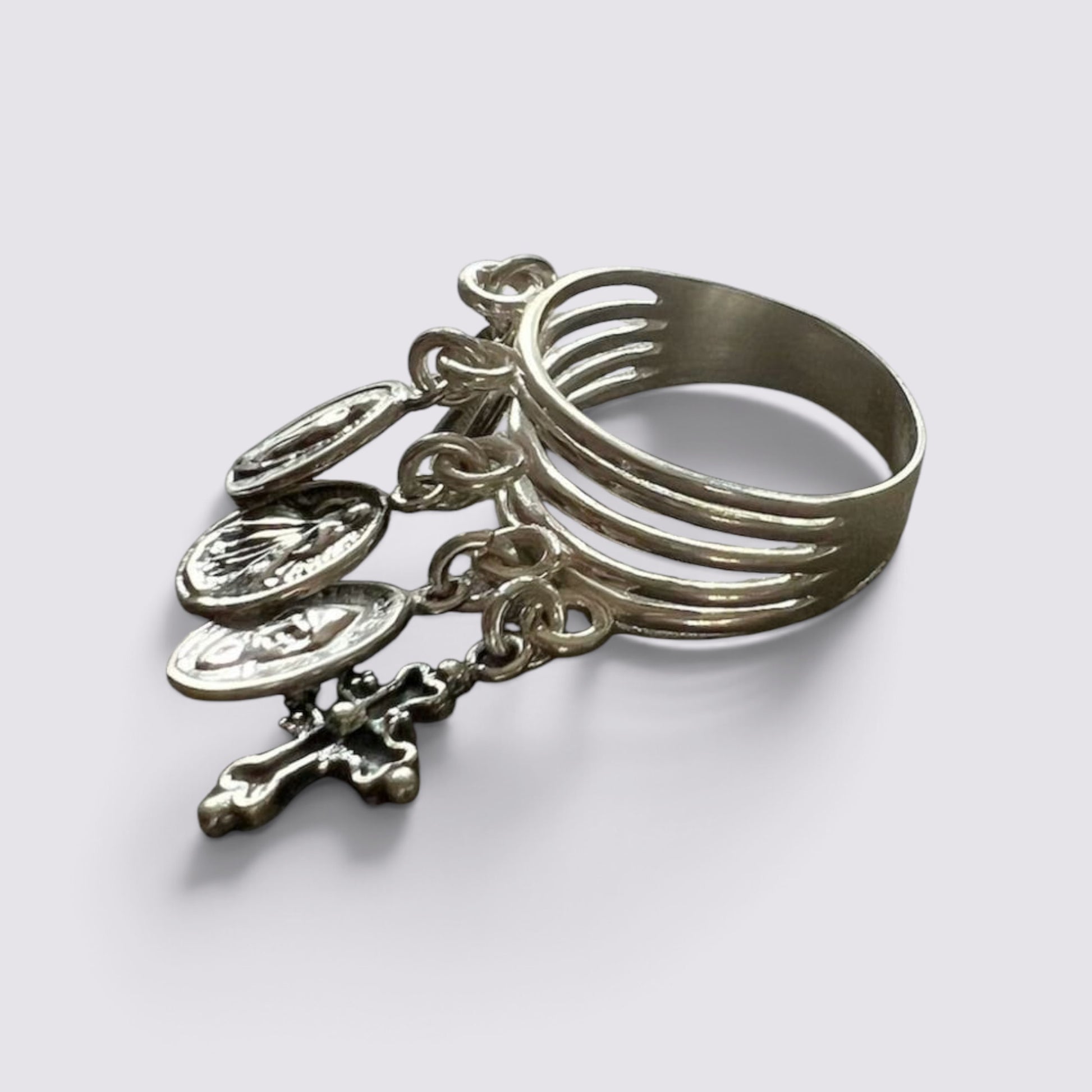 The Fashion Jewels sterling silver ring featuring five hanging religious charms and a cross on a dark grey surface.