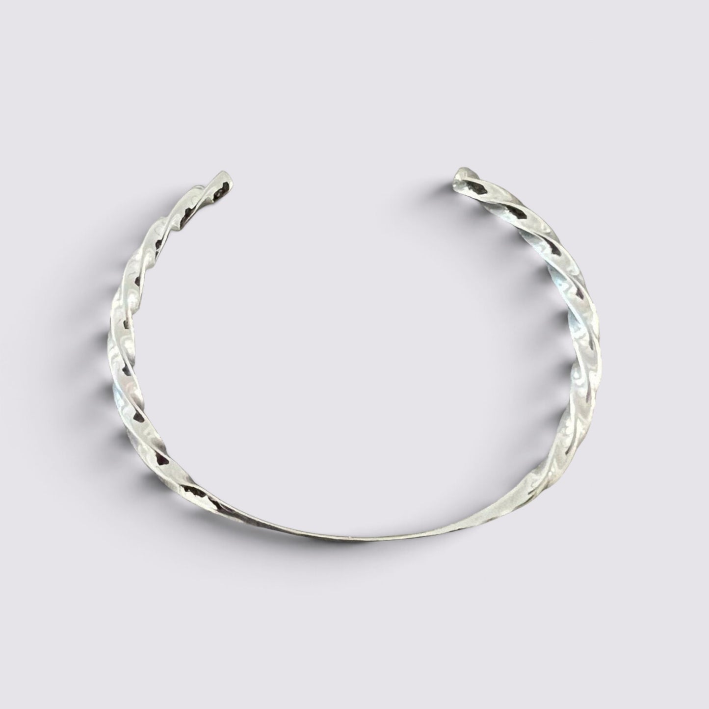 The Fashion Jewels sterling silver open cuff bracelet with a polished twisted metal texture on a light background.