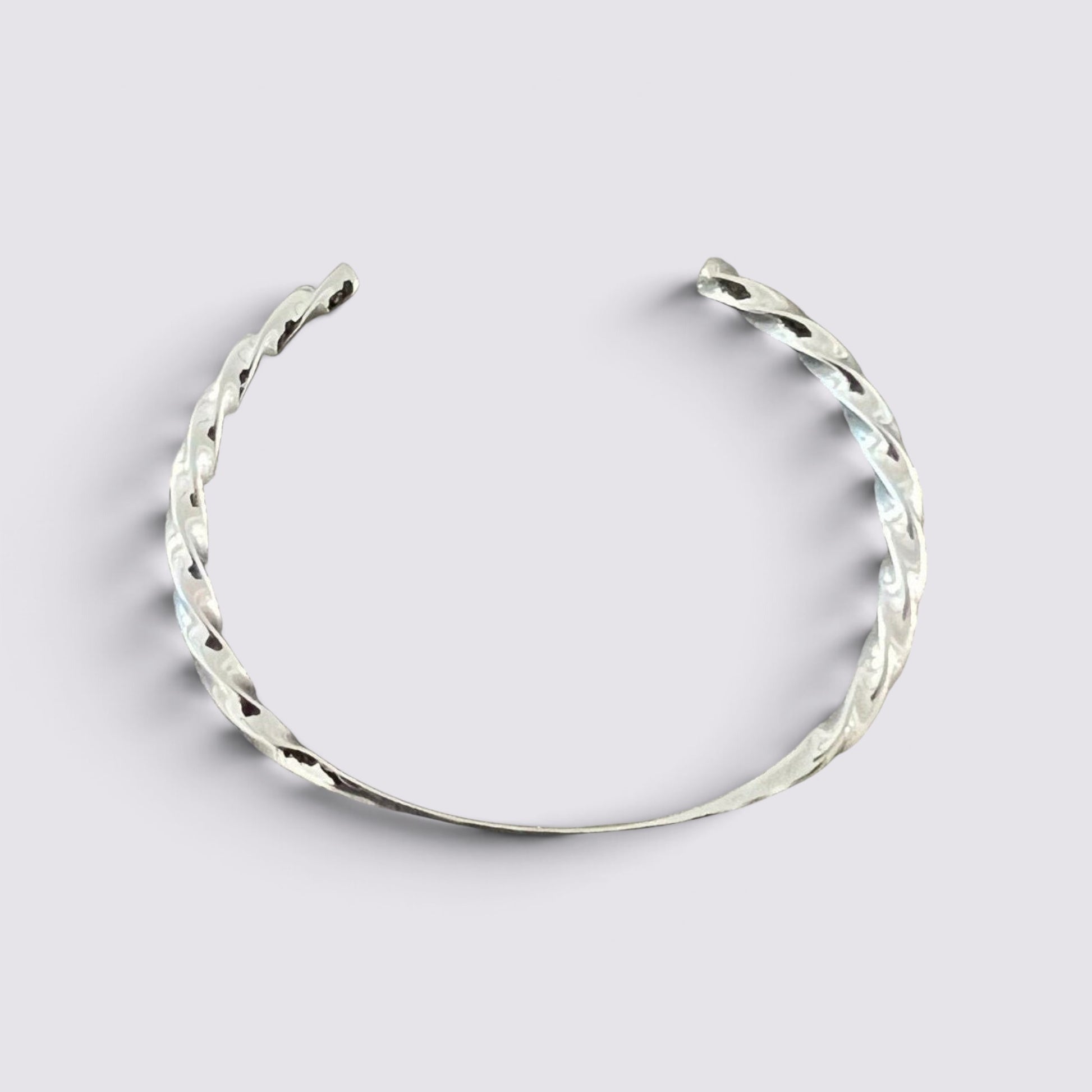 The Fashion Jewels sterling silver open cuff bracelet with a polished twisted metal texture on a light background.